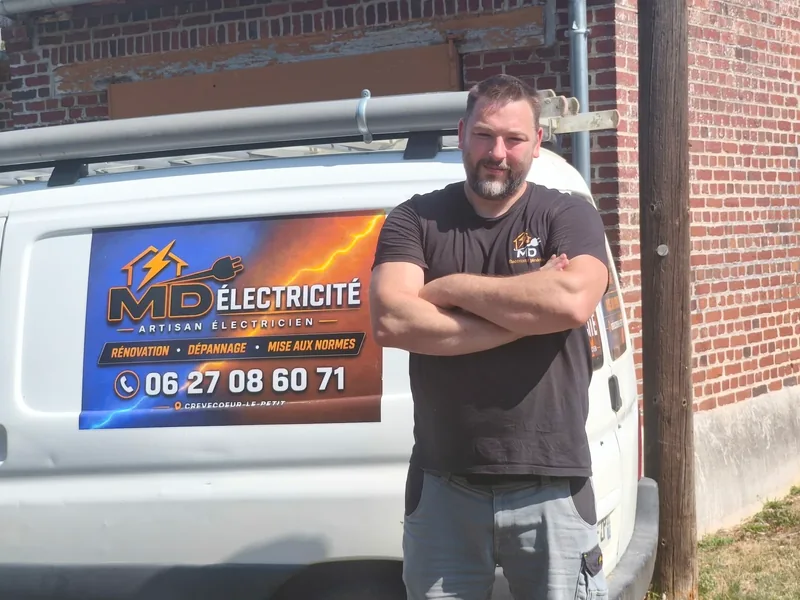 Damien, artisan électricien, devant son véhicule MD Électricité